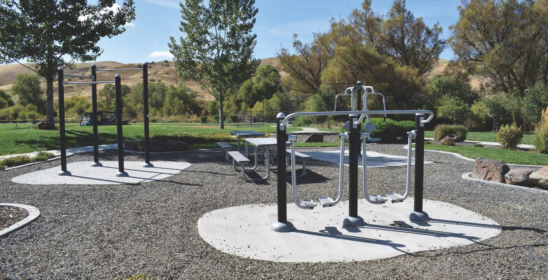 Outdoor fitness stations arranged beside a landscaped park path