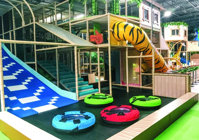 Indoor playground with a tube slide, climbing frames and blue play ramps